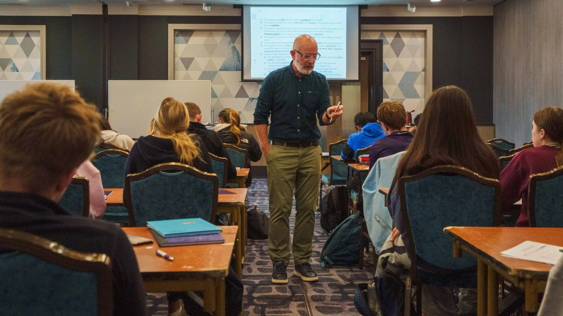 Paul McCormack delivering an English grinds lesson in Dublin to a classroom of secondary school students, with notes projected on a screen.